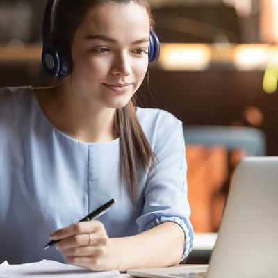 Student looks at her computer and takes notes.